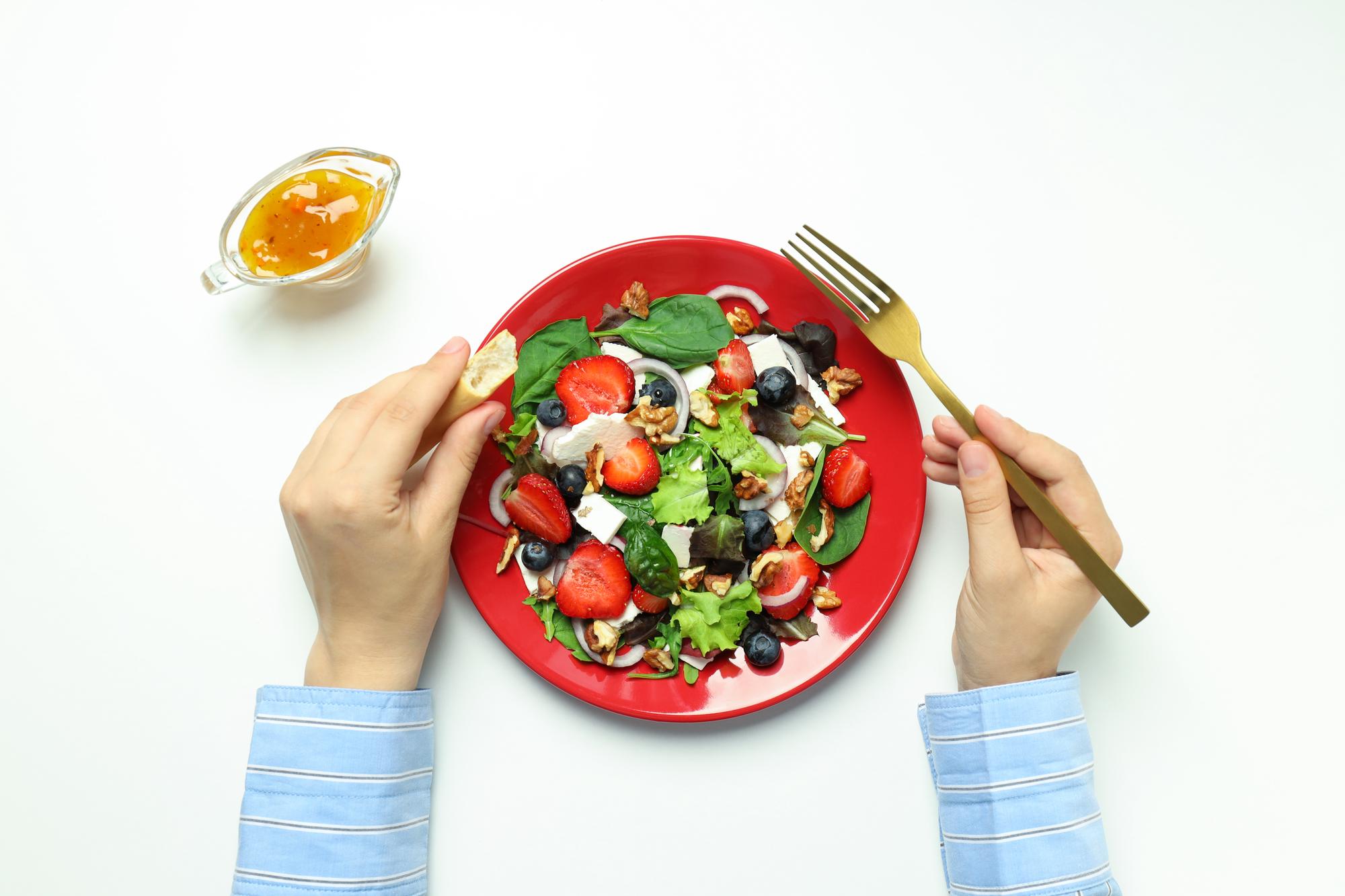 hands plating a colorful salad
